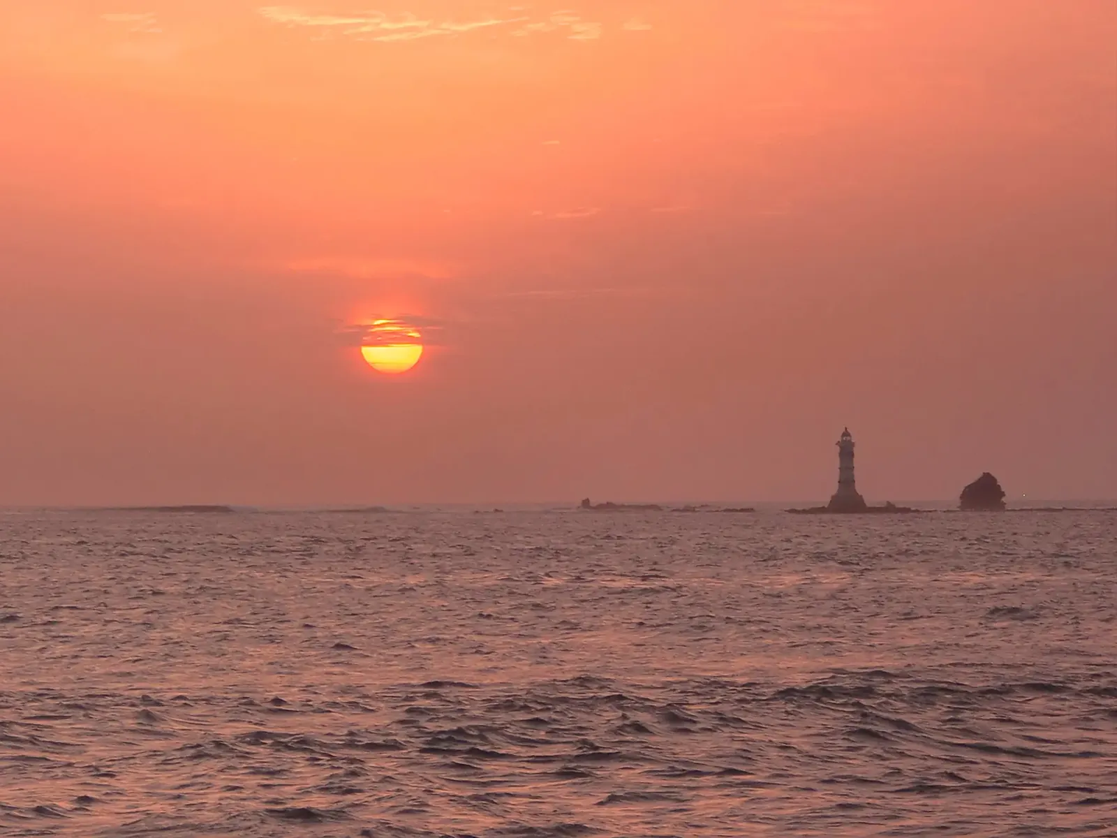 Coucher de soleil sur l'océan à la pointe des Almadies, avec un phare en silhouette